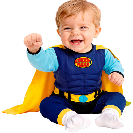 Babysuperheldenpak zittend gedragen, gele cape en geel tailleband met blauwe gesp