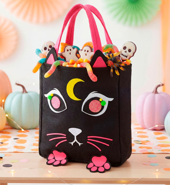 Snoeptas kat gevuld met snoep tussen pompoenen als Halloween-decor