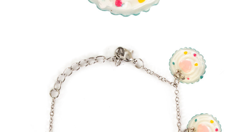 Armband cupcake met roomwitte cupcakebedeltjes, roze hartje en gekleurde spikkels aan zilverkleurig kettinkje
