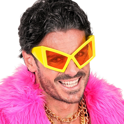 Close-up van de gele oversized feestbril met brede poten en oranje glazen op een man