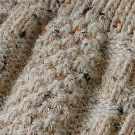 Detail van het gemêleerde beige garen met oranje en zwarte spikkels in de kabelsteek