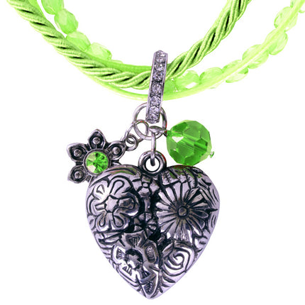 Detail van de hartbedel met bloemenreliëf, bloemetje en groene facetsteen aan de groene tirolerketting