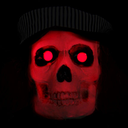 Detail van de skeletkop met rood oplichtende ogen en gestreepte hoedband