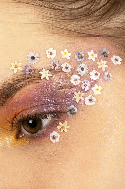 Gedroogde bloemetjes in wax in wit en paars als eyedesign rond het oog, over paarse schmink