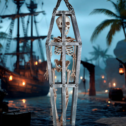 Gekooid skelet hangend in een piratenhaven, skelet met grijnzende schedel achter de spijlen
