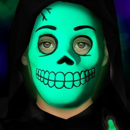 Groen oplichtend schedelmasker op een kind tijdens een halloweenavond