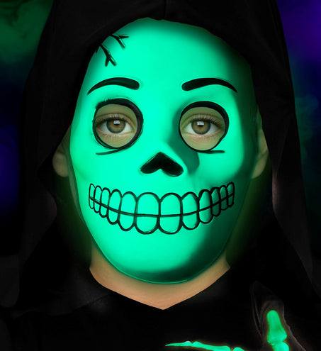 Groen oplichtend schedelmasker op een kind tijdens een halloweenavond
