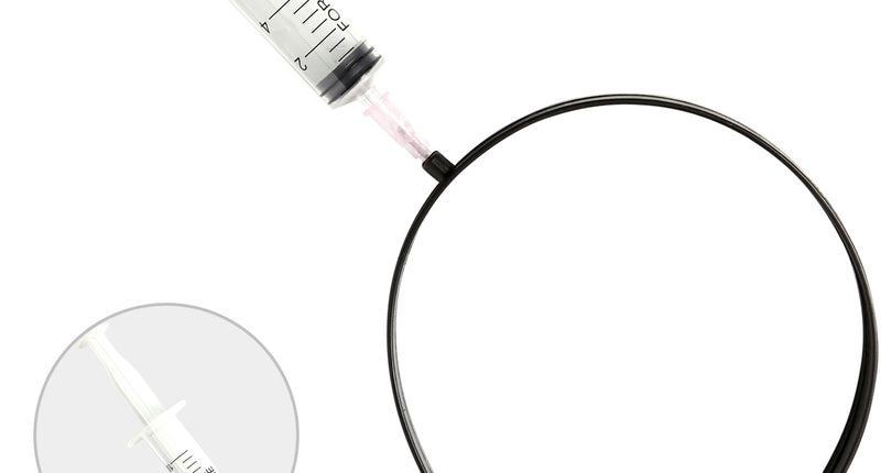 Injectienaald door hoofd: zwarte metalen haarband met doorzichtige nepspuit met maatstreepjes