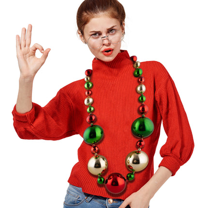 Kerstballen halsketting gedragen over een rode trui, grote ballen op buikhoogte, voor een kerstfeest