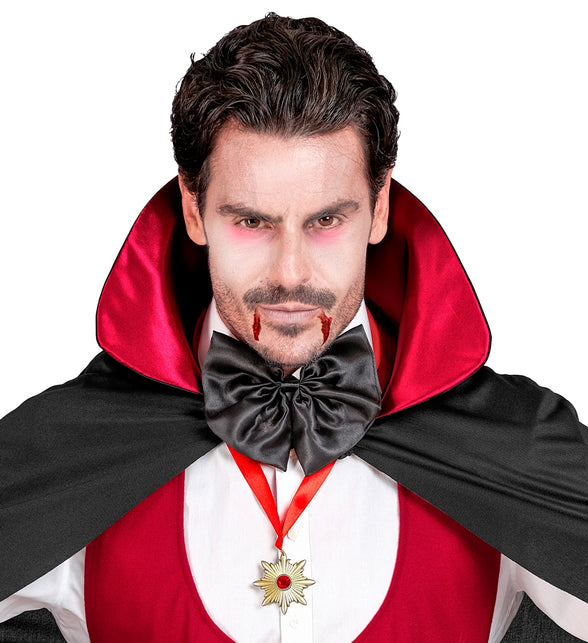 Ketting Dracula medaillon over rood vest, rood lint zichtbaar in de hals bij griezelschmink