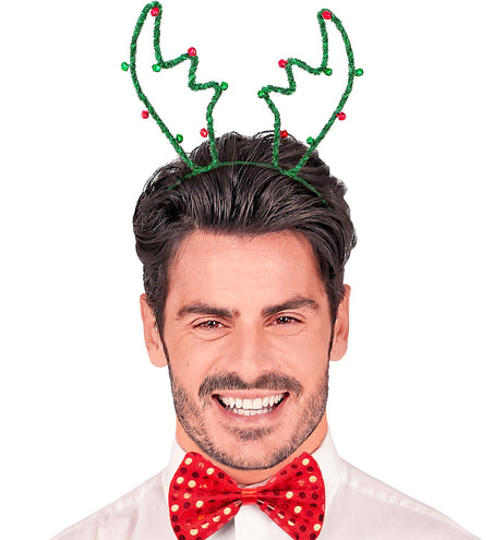 Man met groen rendiergewei op zijn hoofd en rode vlinderdas op een kerstfeest