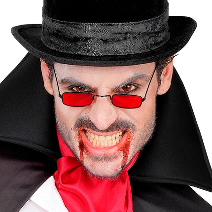 Man met rode vampieren bril, hoge hoed en nepbloed voor een griezelige Halloweenlook