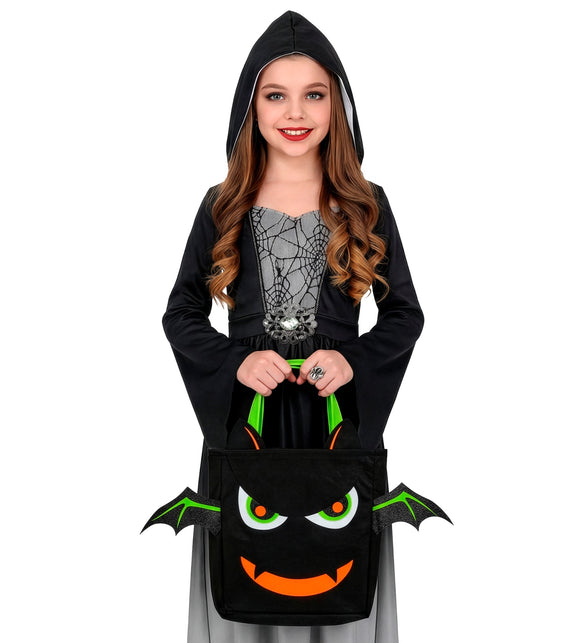 Meisje draagt de zwarte vleermuis snoeptas met twee handen tijdens Halloween