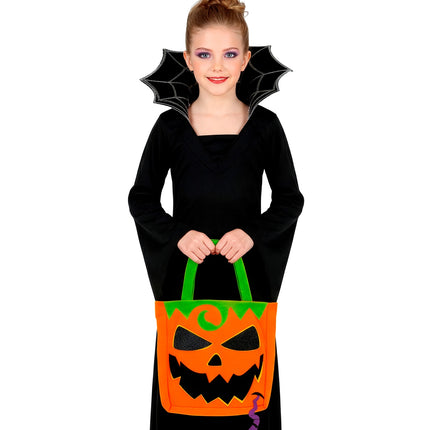 Meisje houdt trick-or-treat tas pompoen vast bij zwarte Halloweenjurk