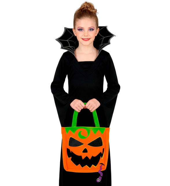 Meisje houdt trick-or-treat tas pompoen vast bij zwarte Halloweenjurk