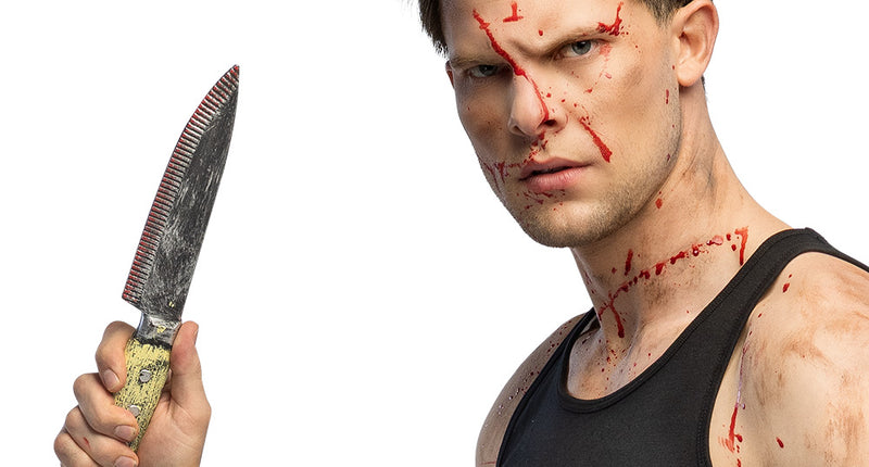 Mes Grimblade met zilvergrijs lemmet en geel heft, rechtop vastgehouden bij een slasherlook voor Halloween