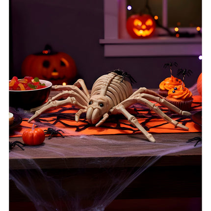 Spinnen skelet op een halloweentafel met spinrag, pompoenen en cupcakes