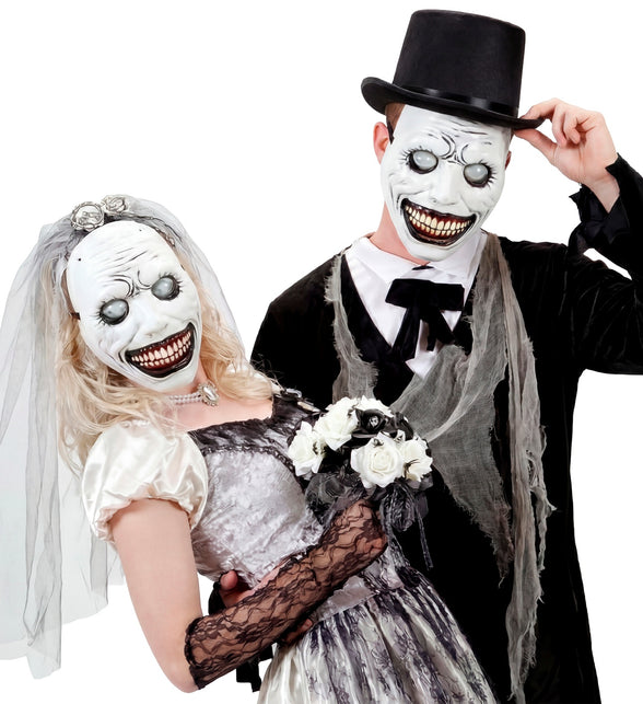 Twee grijnzende monstermaskers met grijze bolle ogen bij een griezelig bruidspaar op Halloween