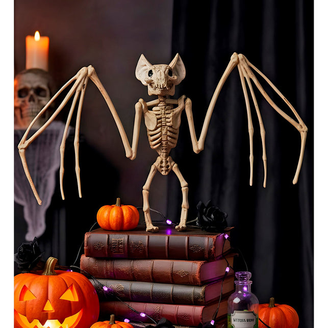 Vleermuis skelet als halloweendecoratie op een boekenstapel tussen pompoenen en kaarslicht